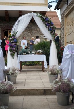 elegantní oblouková slavobrána dozdobená voály a květinami.